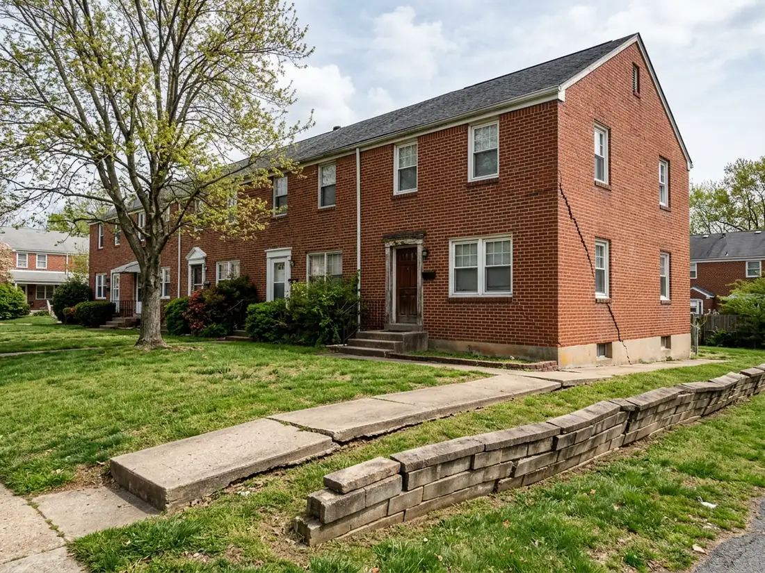Row of brick townhomes with a settled corner, a sunken concrete walk and a leaning retaining wall on common ground