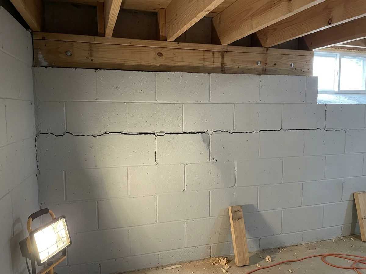 Long horizontal crack along a mortar joint three courses below the top of a concrete block basement wall